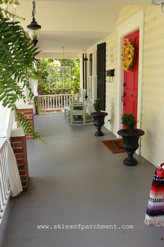 grey cottage porch with white railing and red door